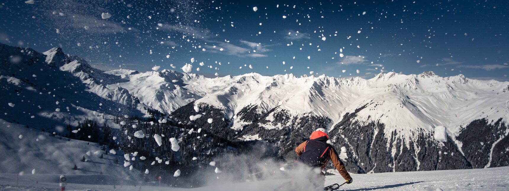 Ein Skifahrer auf der Piste und spritzender Schnee im Vordergrund. | © Silvretta Montafon - Daniel Hug