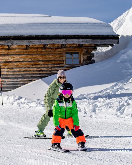 Ein Kind auf Ski übt mit ihrer Mutter den Pflug auf einer Anfängerpiste. | © Silvretta Montafon - Torsten Wenzler