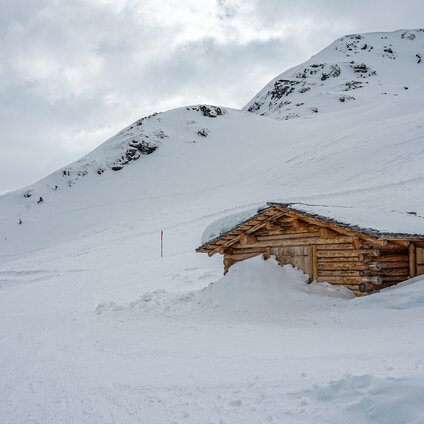 Verschneiter Winterwanderweg und eine Holzhütte in den Bergen der Silvretta Montafon. | © Silvretta Montafon - Vanessa Strauch