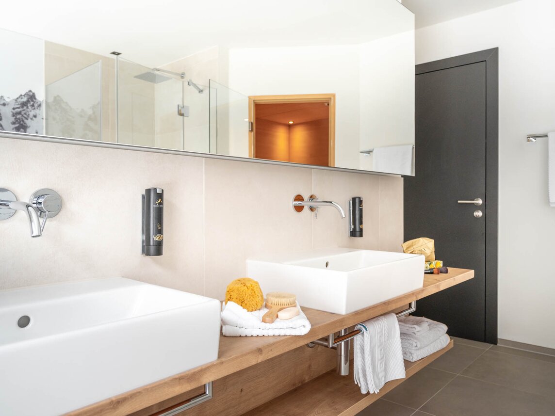 Ein geräumiges Badezimmer mit zwei Waschbecken, großen Spiegel und Holzschränken | © Silvretta Montafon - blateral