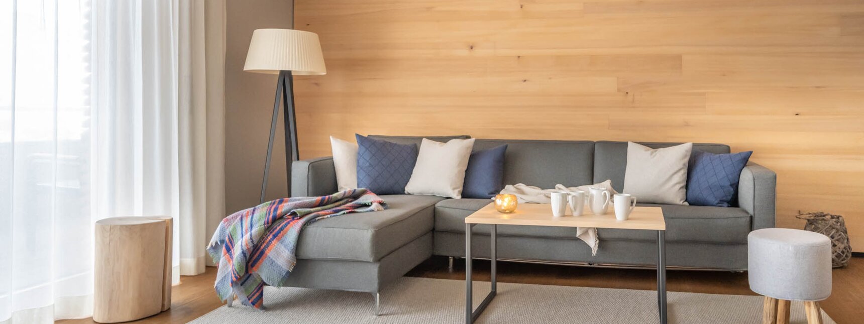 Eine große graue Couch auf einem hellgrauen Teppich und einem Mensch Ärger Dich Nicht Spiel im Vordergrund | © Silvretta Montafon - blateral