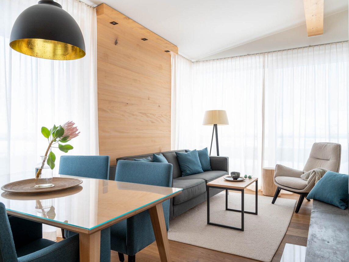 Ein gemütlicher Wohnessbereich mit einer grauen Couch und einem Holzesstisch | © Silvretta Montafon - blateral