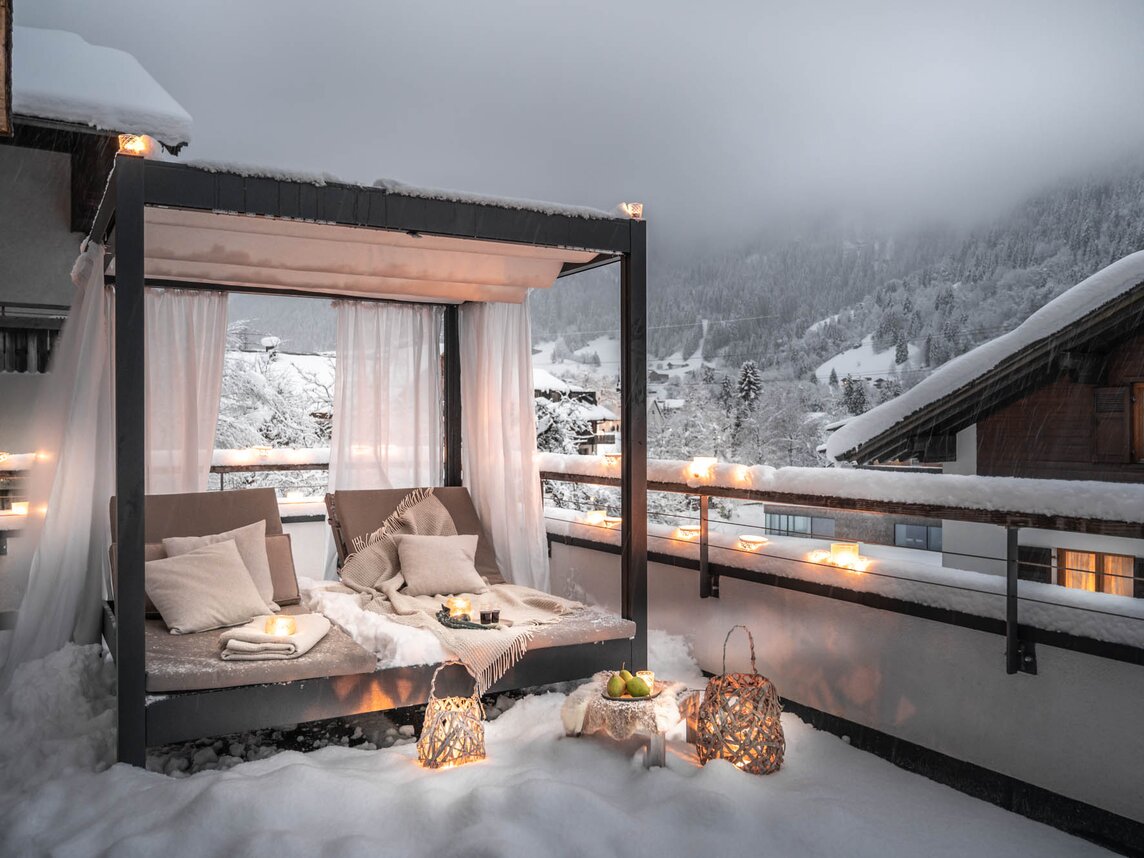 Ein romantisches beleuchtetes Bett im freien im Schnee auf der Terrasse mit Aussicht auf die verschneiten Berge | © Silvretta Montafon - blateral