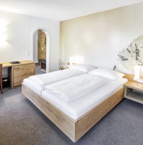 Gemütliche Familiensuite mit Doppelbett und einem schönen Schreibtisch | © Silvretta Montafon - Markus Gmeiner