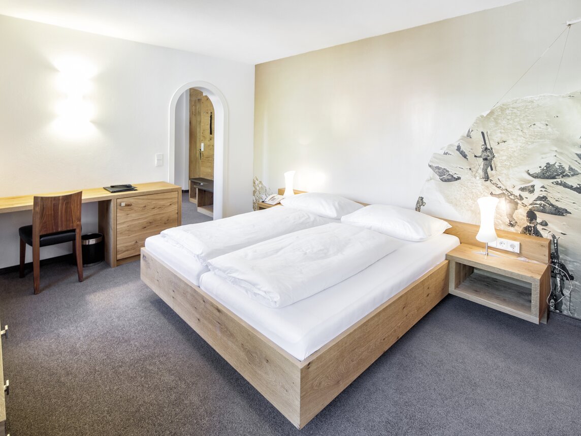 Gemütliche Familiensuite mit Doppelbett und einem schönen Schreibtisch | © Silvretta Montafon - Markus Gmeiner